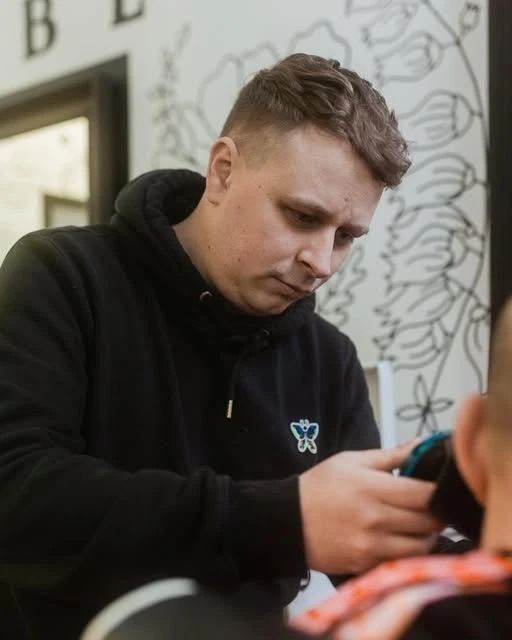 Craig concentrating on a haircut in front of the shop’s illustrated walls