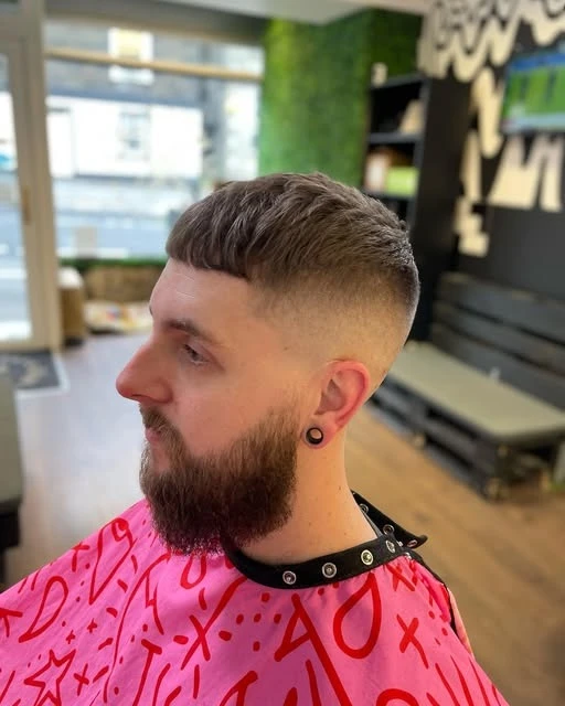 Side view of a faded haircut with a swept-back top and full beard