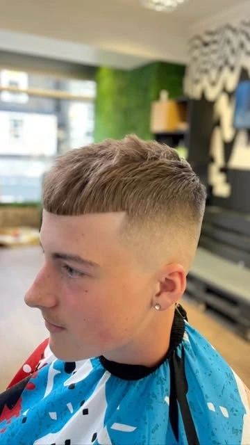 A short straight fringe and skin fade, photographed from the side