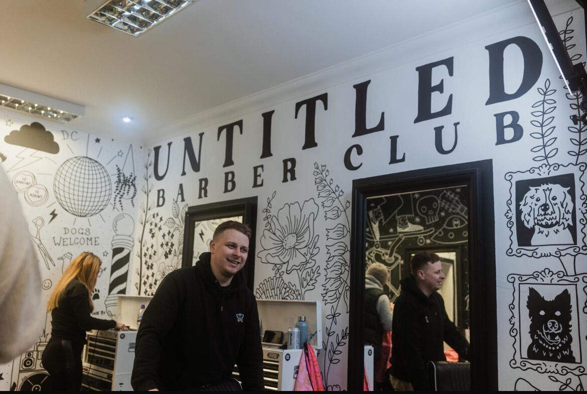 Craig inside Untitled Barber Club, with the original shop lettering and illustrated walls